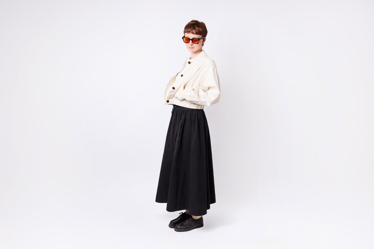 Person wearing a white jacket and black skirt on a white background