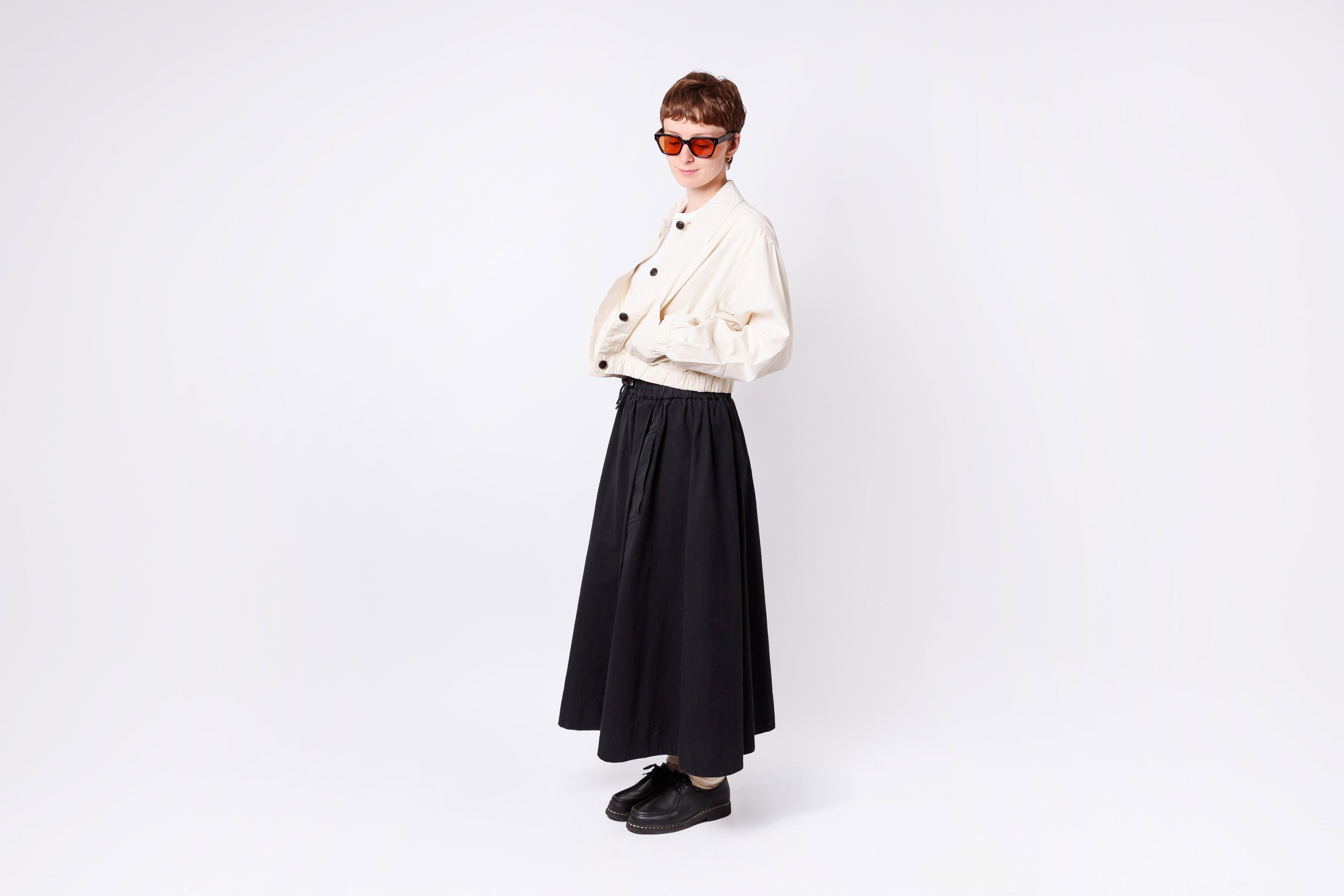 Person wearing a white jacket and black skirt on a white background