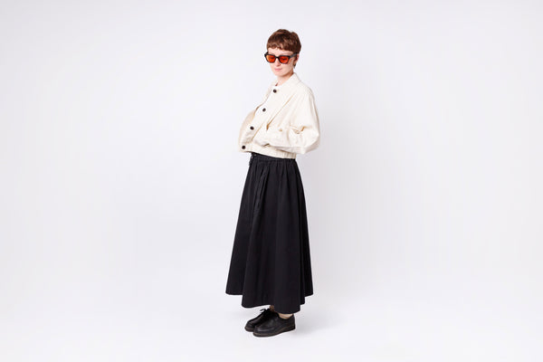 Person wearing a white jacket and black skirt on a white background