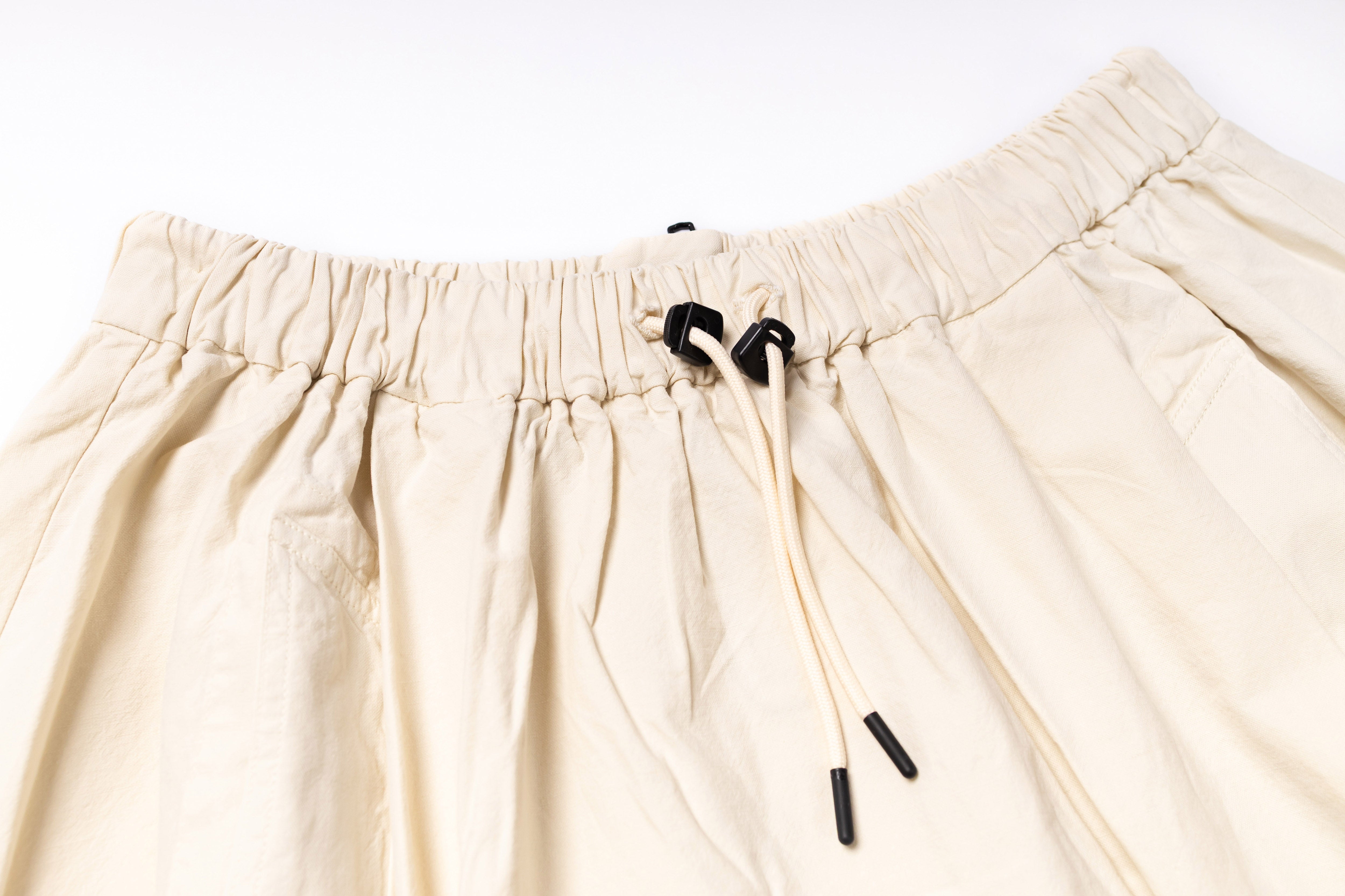 Close-up of beige shorts with drawstring on a white background