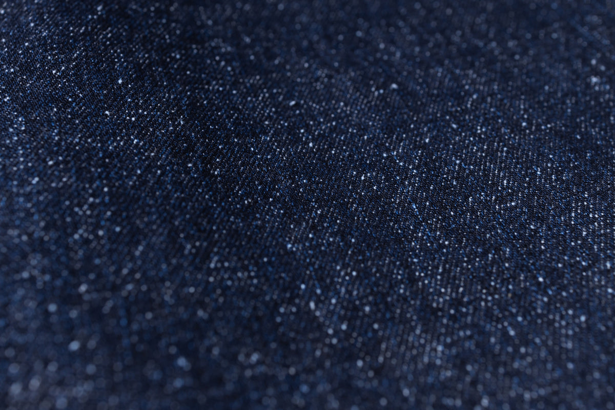 Close-up of dark indigo denim fabric texture with subtle sheen and fine weave details.