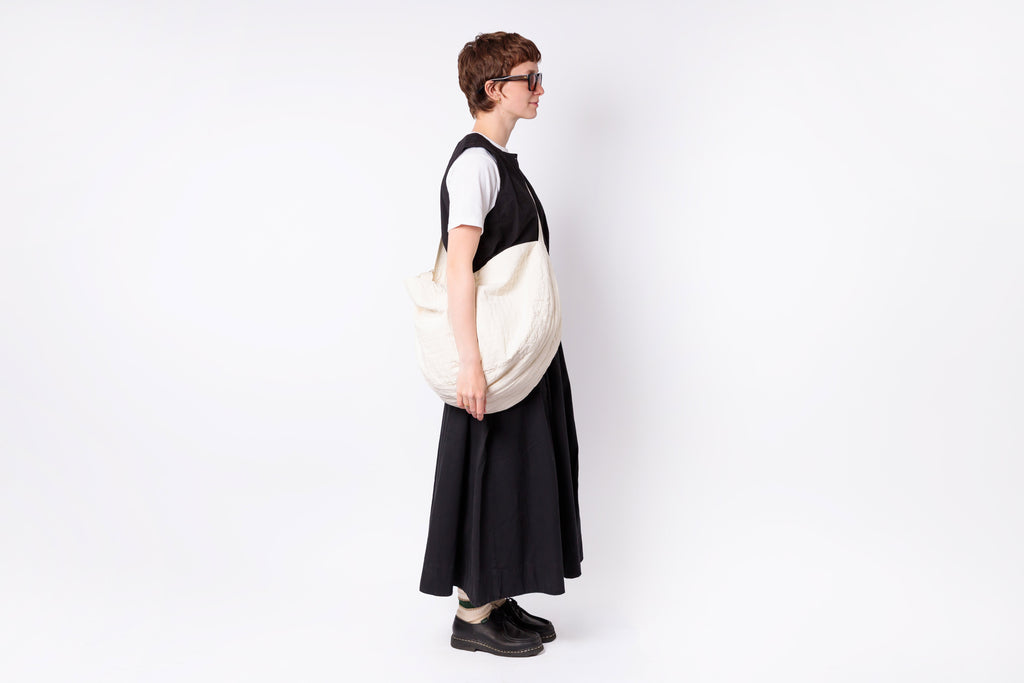 Person wearing a black and white dress holding a matching bag on a white background