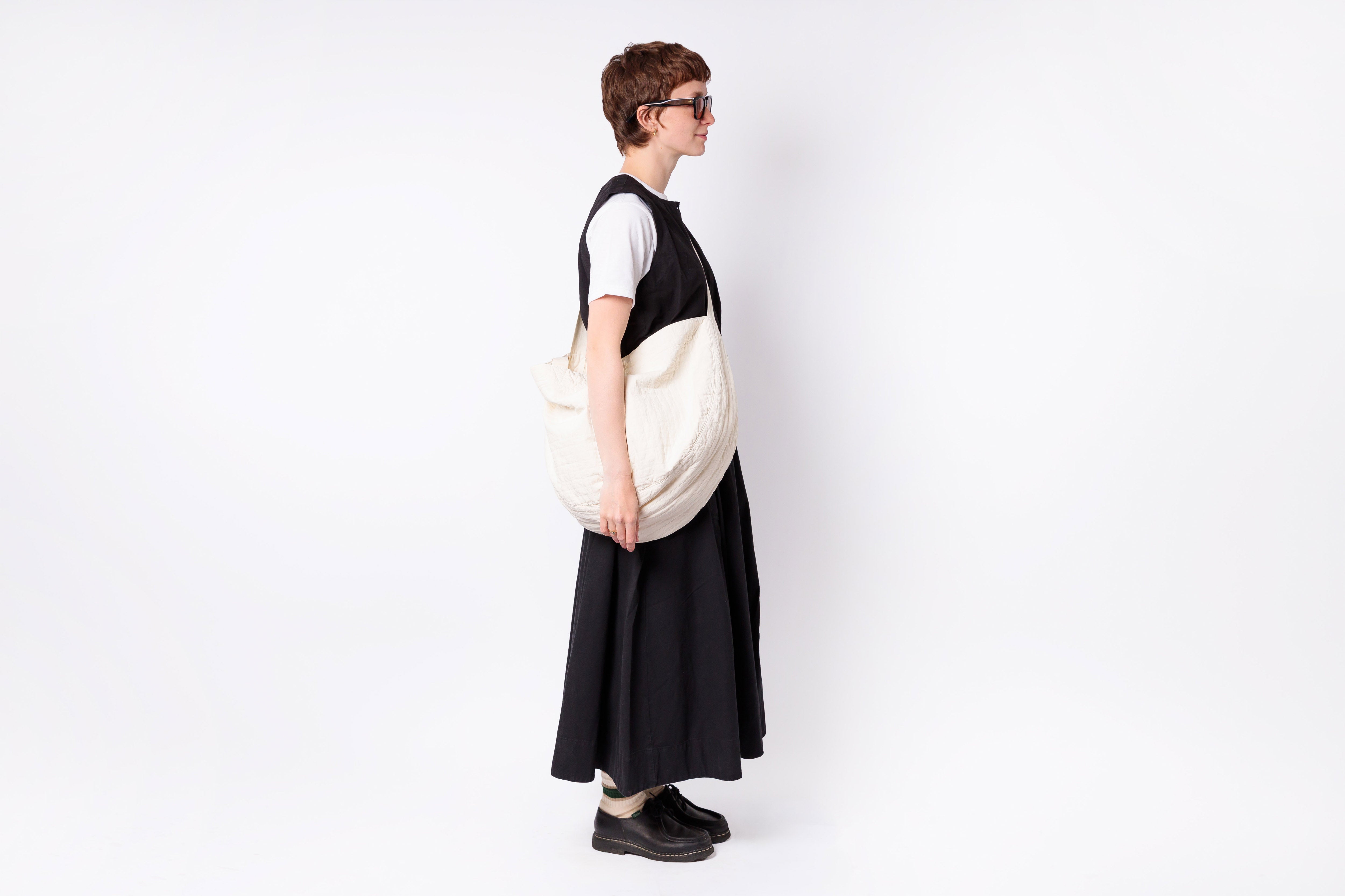 Person wearing a black and white dress holding a matching bag on a white background