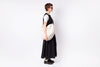 Person wearing a black and white dress holding a matching bag on a white background