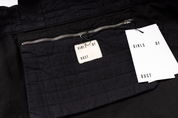 Black jacket with a brand tag and paper on a black background
