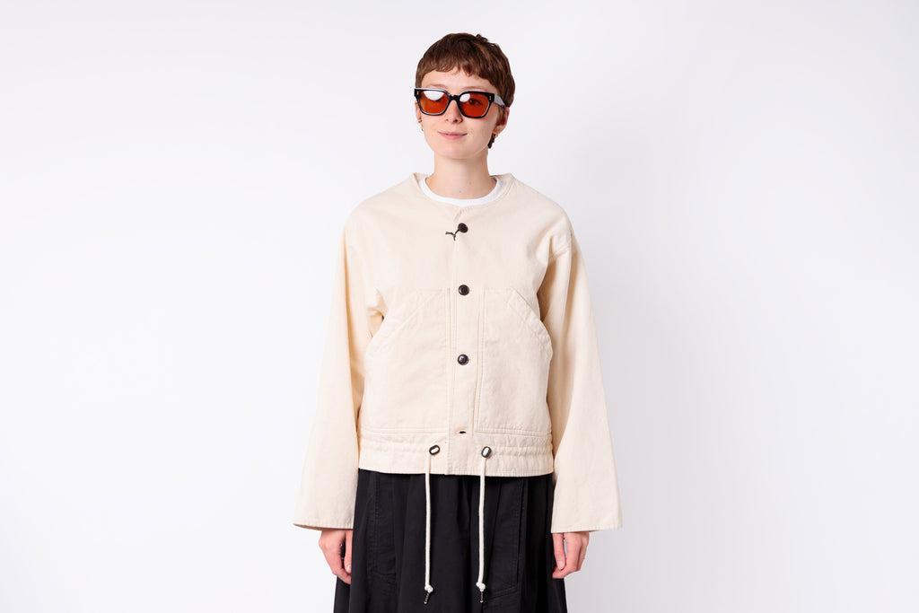 Person wearing a beige jacket and sunglasses on a white background