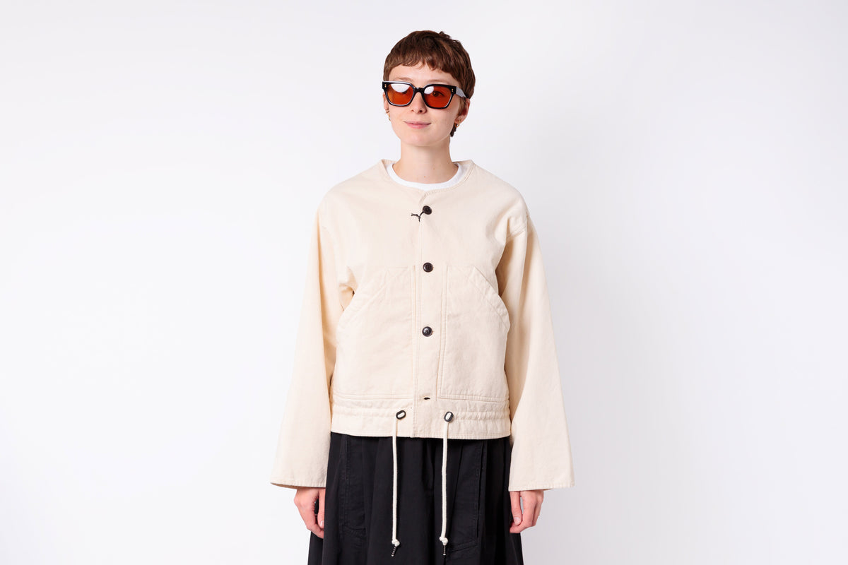 Person wearing a beige jacket and sunglasses on a white background