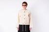 Person wearing a beige jacket and sunglasses on a white background