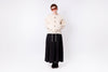 Person wearing a beige cardigan, black skirt, and sunglasses on a white background