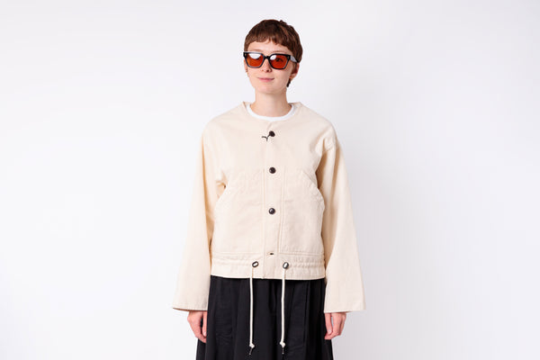 Person wearing a beige jacket and sunglasses on a white background