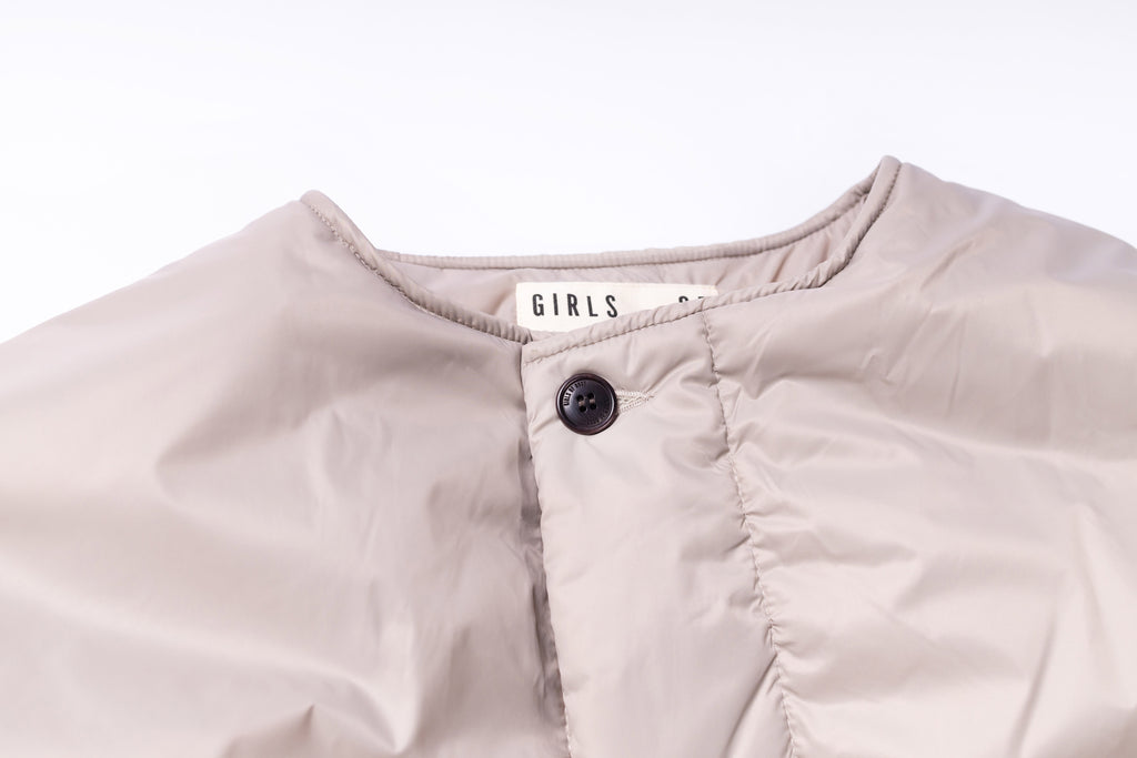 Close-up of a light pink jacket with a button on a white background