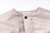 Close-up of a light pink jacket with a button on a white background