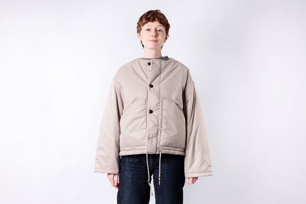 Person wearing a beige jacket on a white background