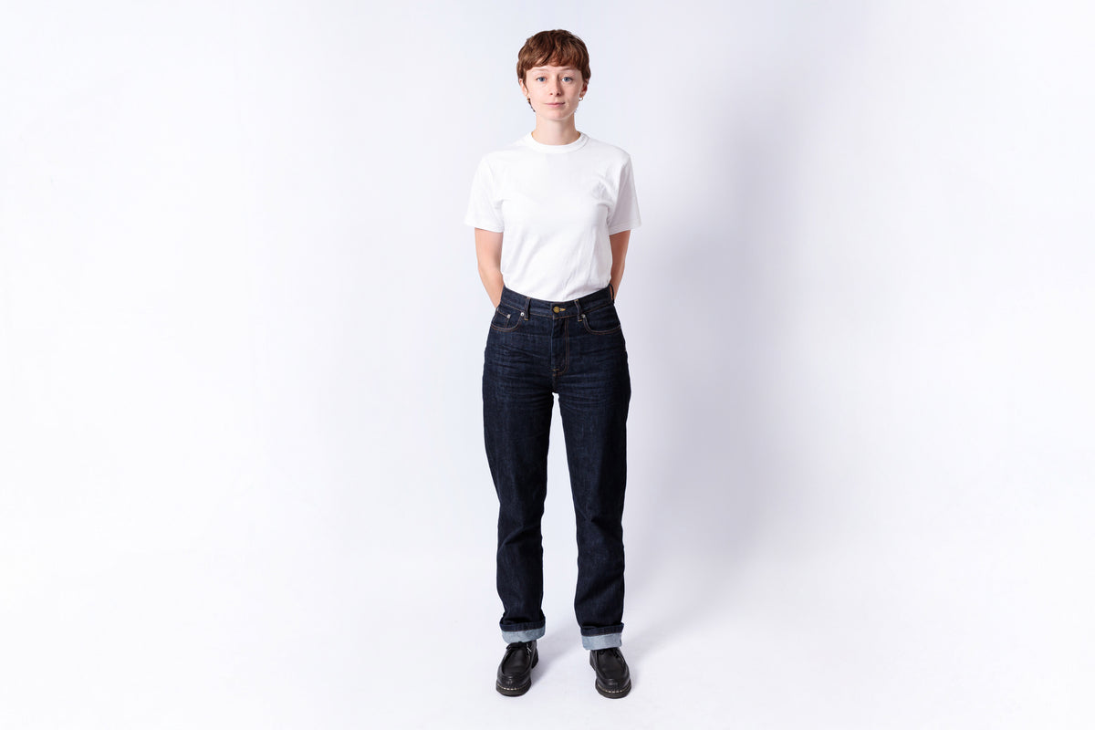 Person wearing a white t-shirt and dark jeans on a white background