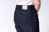 Person wearing dark blue jeans with a visible brand label on a white background