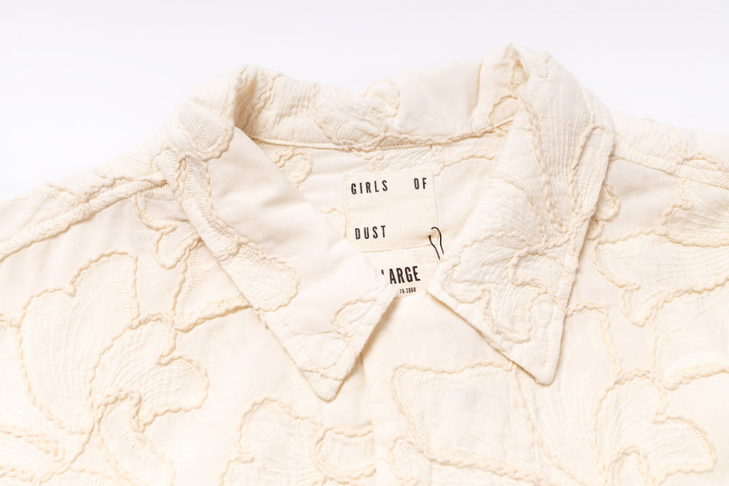 Close-up of a textured cream-colored fabric with 'Girls of Dust' branding.