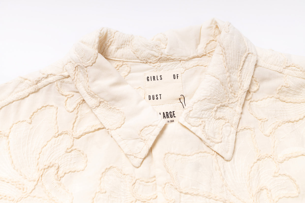 Close-up of a textured cream-colored fabric with 'Girls of Dust' branding.