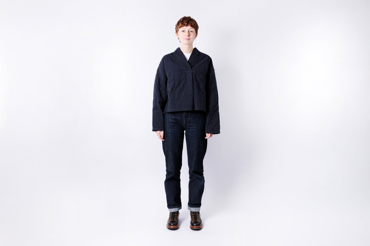 Person wearing a dark jacket and jeans on a white background