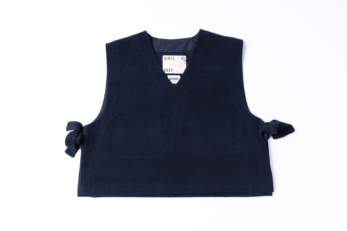 A sleeveless dark navy knit vest with side tie details, laid flat on a white background.