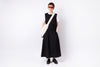 Person wearing a black dress and sunglasses holding a white bag on a white background