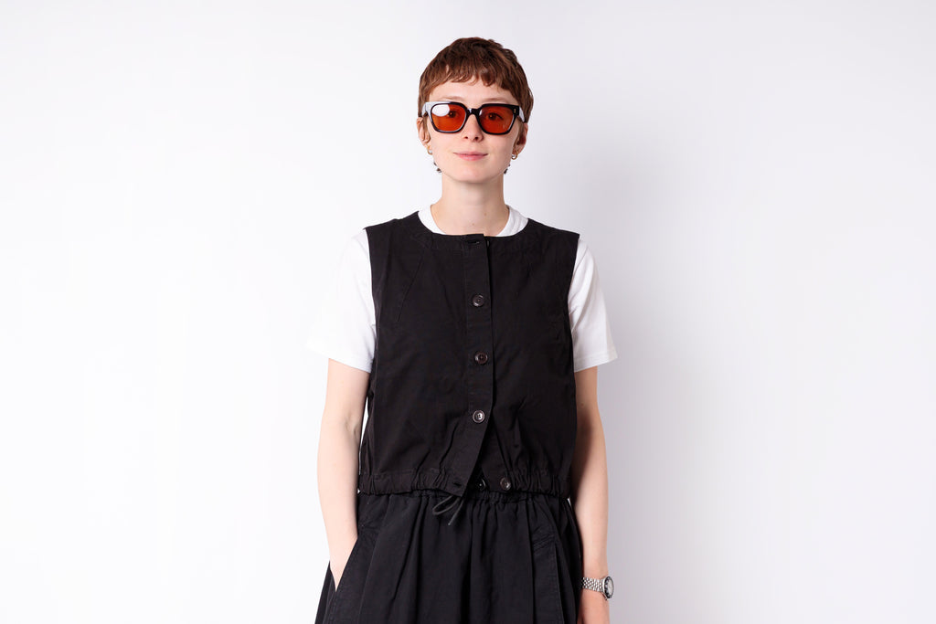 Person wearing a black vest over a white shirt on a white background