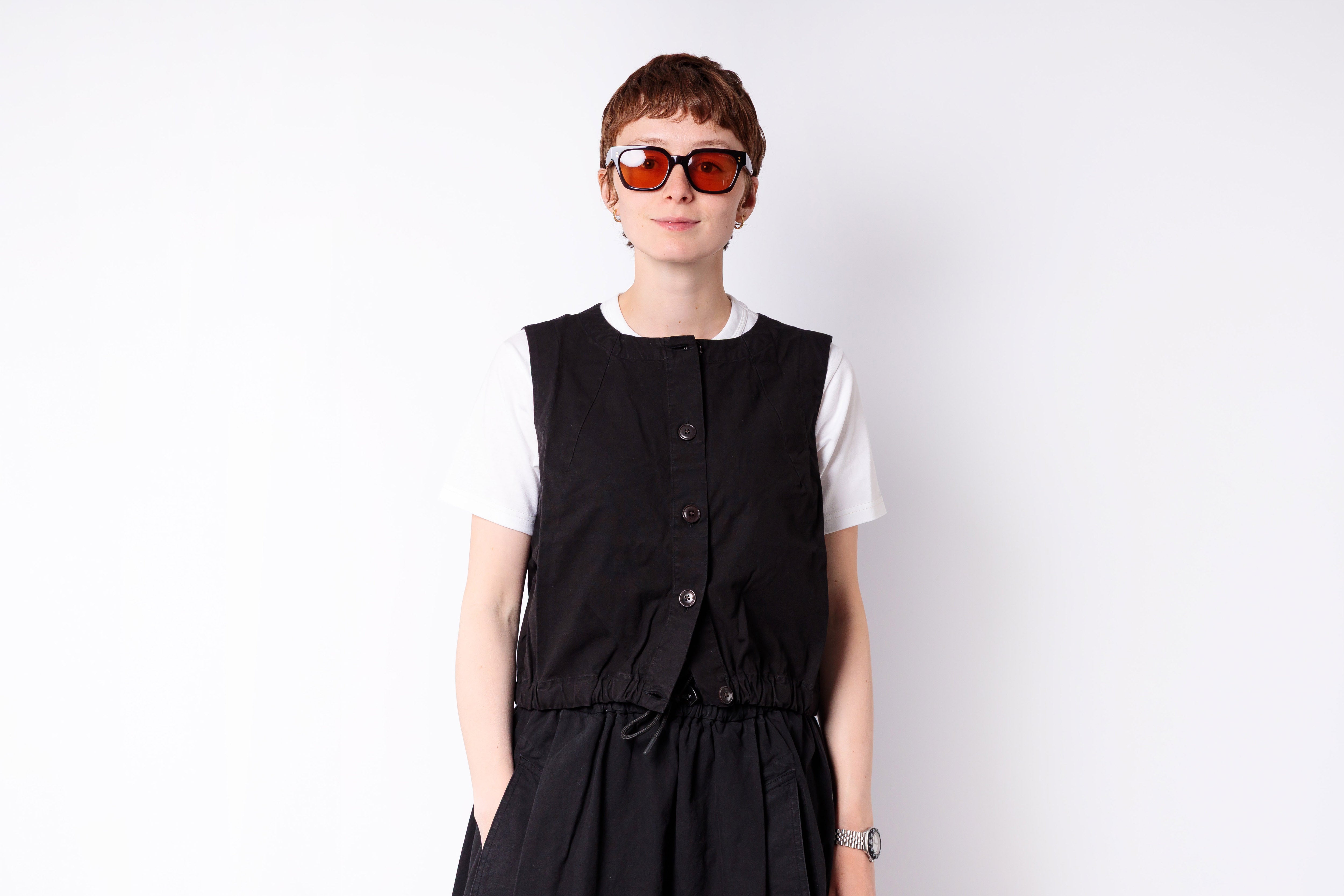 Person wearing a black vest over a white shirt on a white background