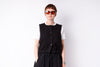Person wearing a black vest over a white shirt on a white background