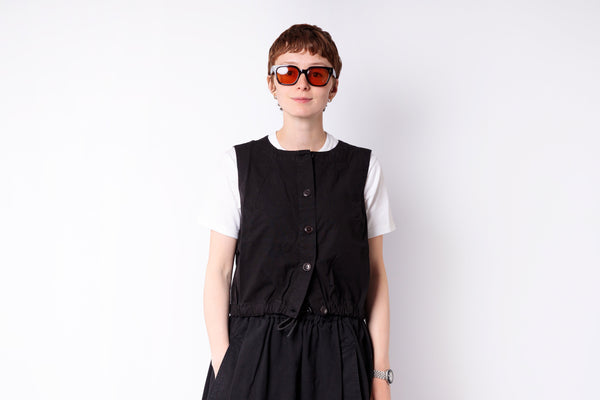 Person wearing a black vest over a white shirt on a white background