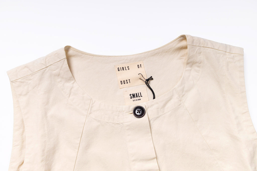 Beige sleeveless top with a tag on a white background