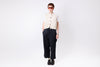 Person wearing a cream shirt and dark pants on a white background