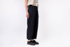 Person wearing dark pants and black shoes on a white background