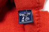 Close-up of a red fabric with a Guesey Woollens label featuring a dog and text.