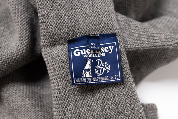 Close-up of a Guernsey Woollens label on a gray fabric background