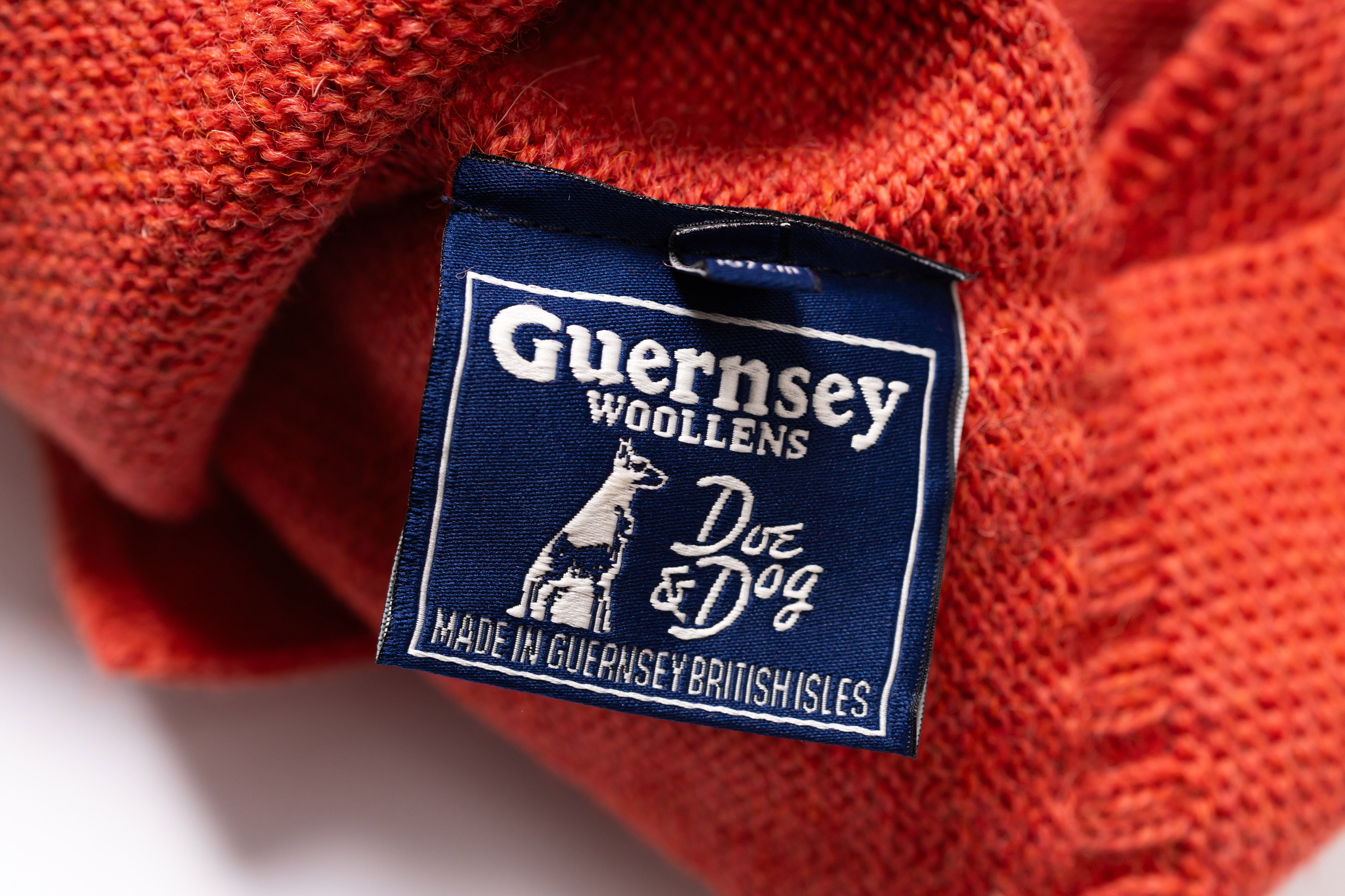 Close-up of a Guernsey Woollens label on a red knitted fabric.