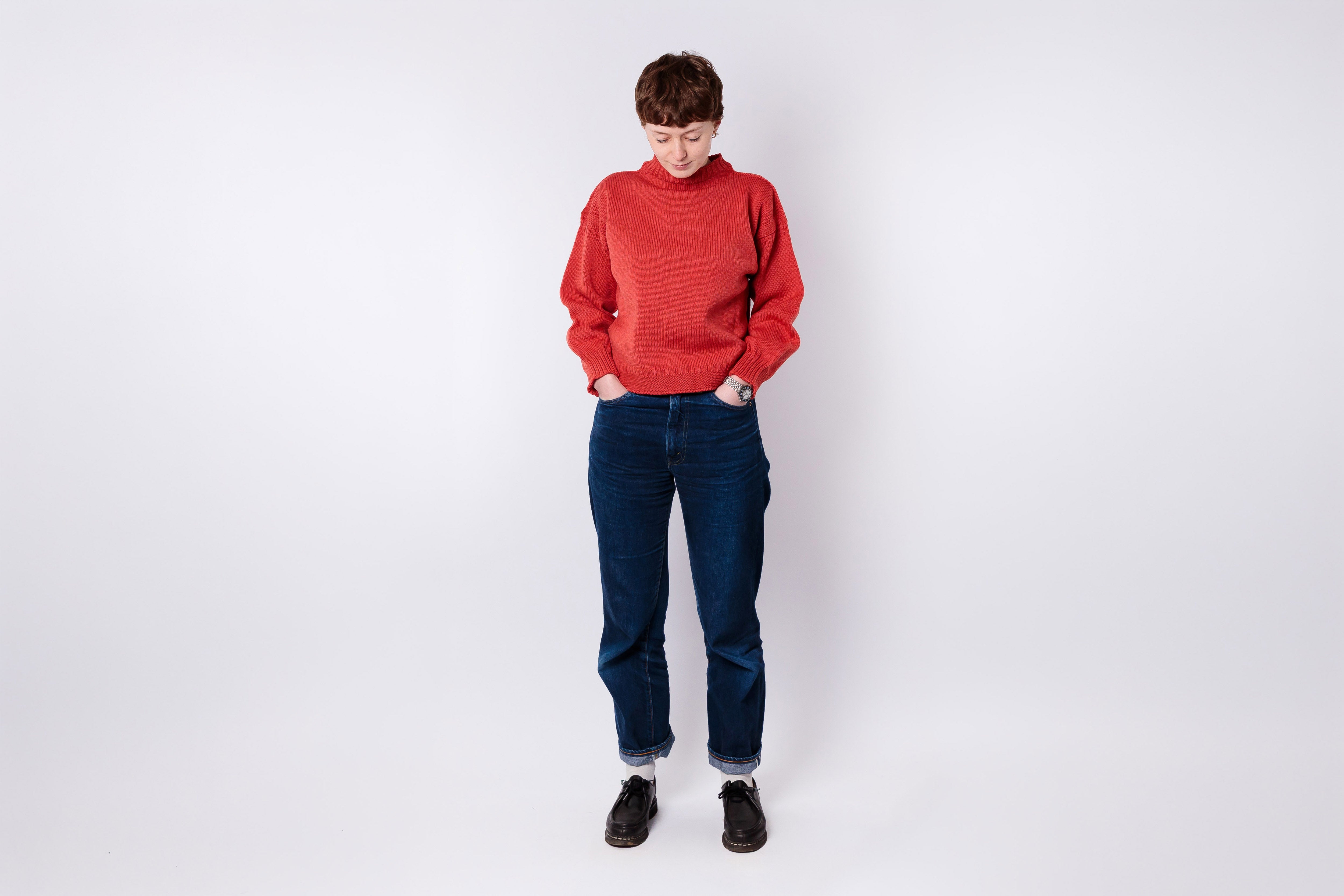 Person wearing a red sweater and blue jeans on a white background