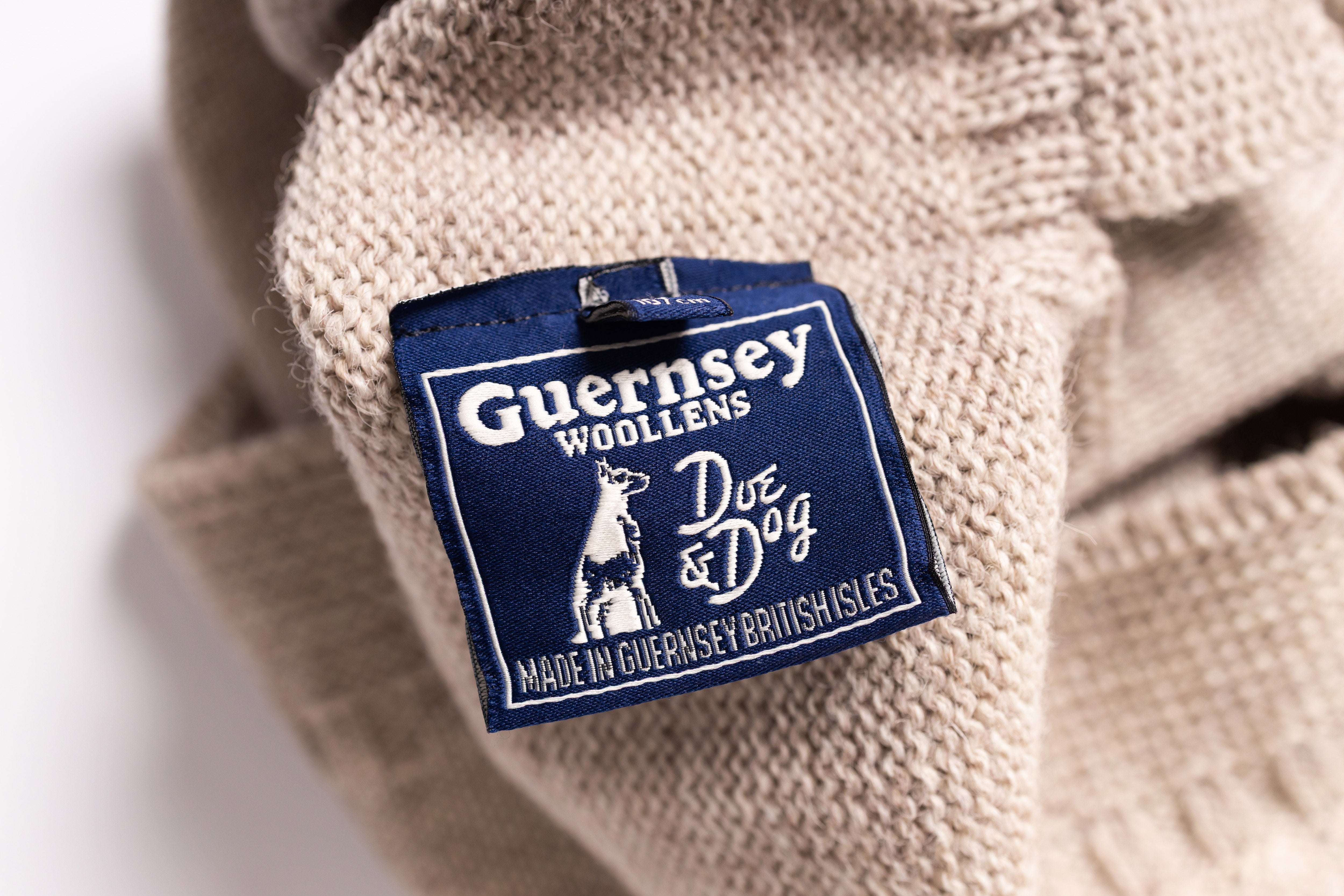Close-up of a Guernsey Woollens label on a beige fabric background