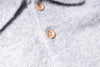 Close-up of a gray knitted sweater with wooden buttons.