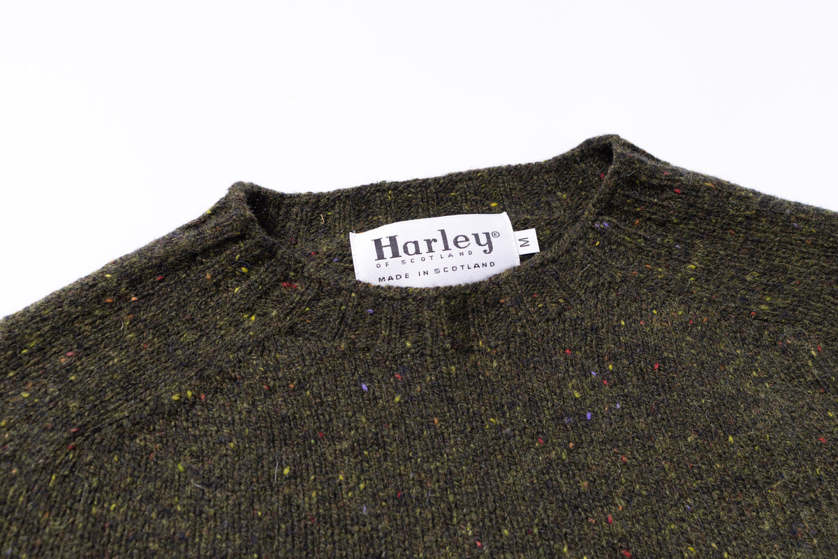 Close-up of a green sweater with a Harley label on a white background