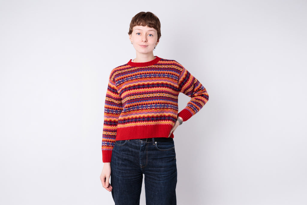 Person wearing a colorful striped sweater and jeans on a white background