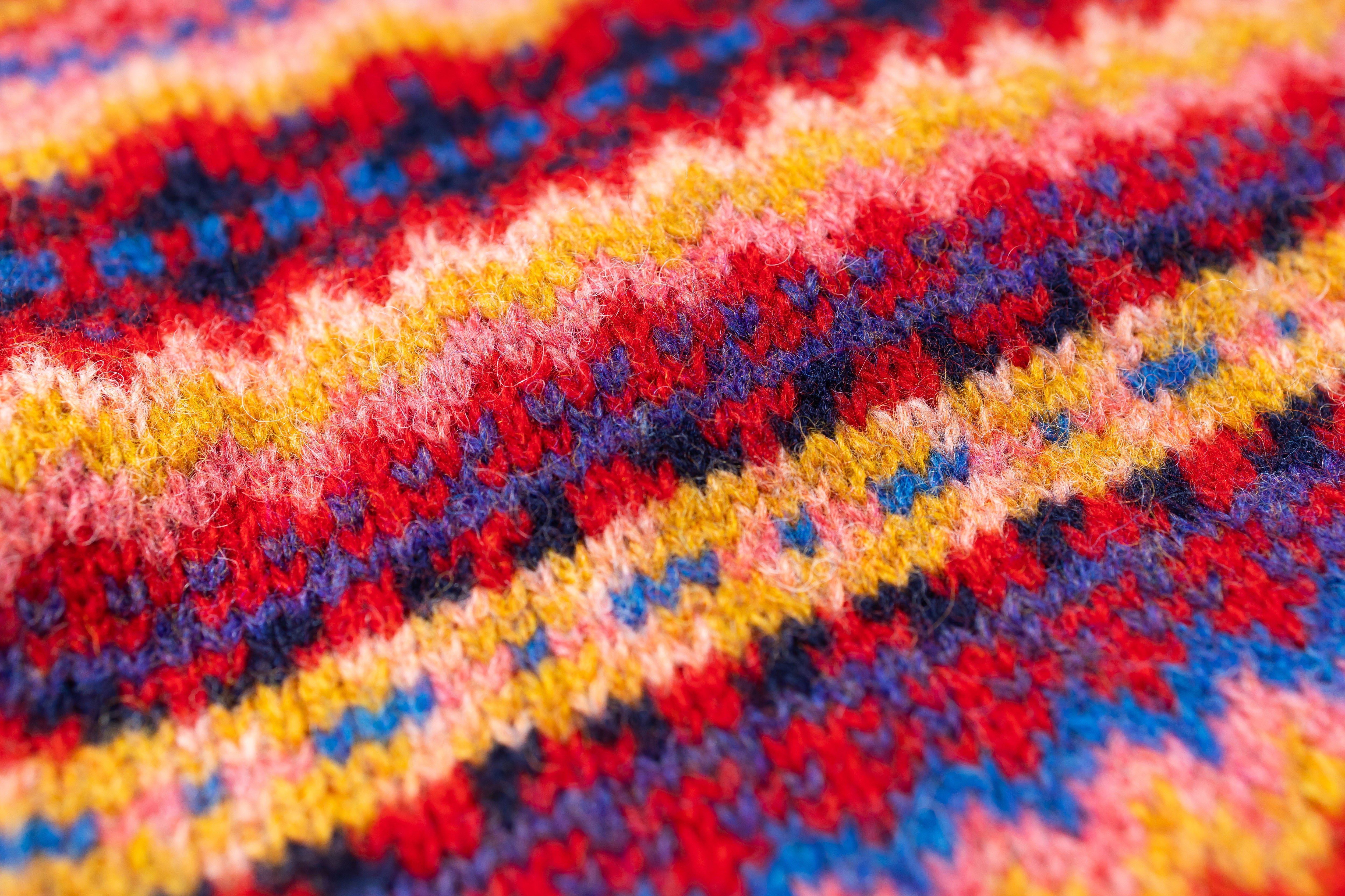 Close-up of a colorful knitted fabric with red, yellow, blue, and pink patterns.