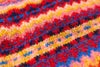 Close-up of a colorful knitted fabric with red, yellow, blue, and pink patterns.