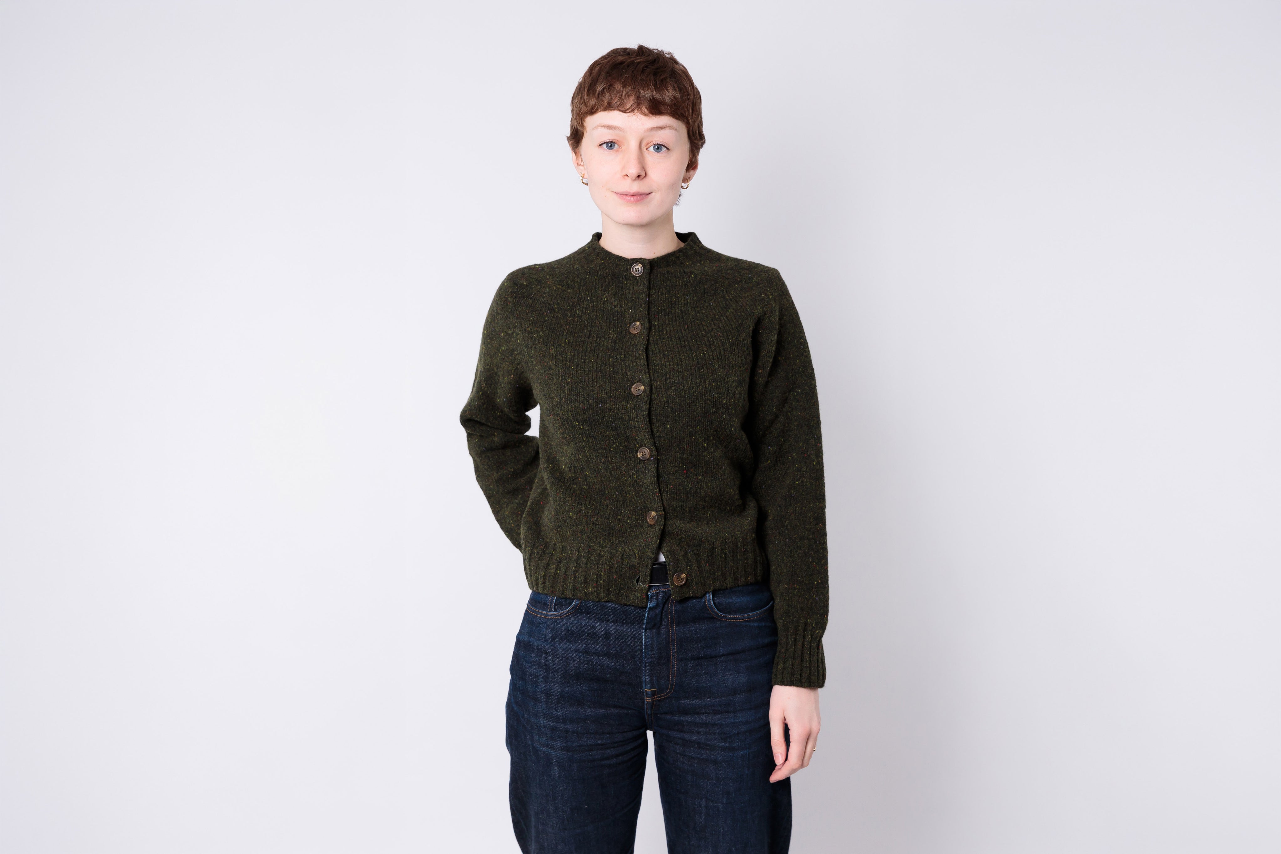 Woman wearing a knitted green cardigan on a white background