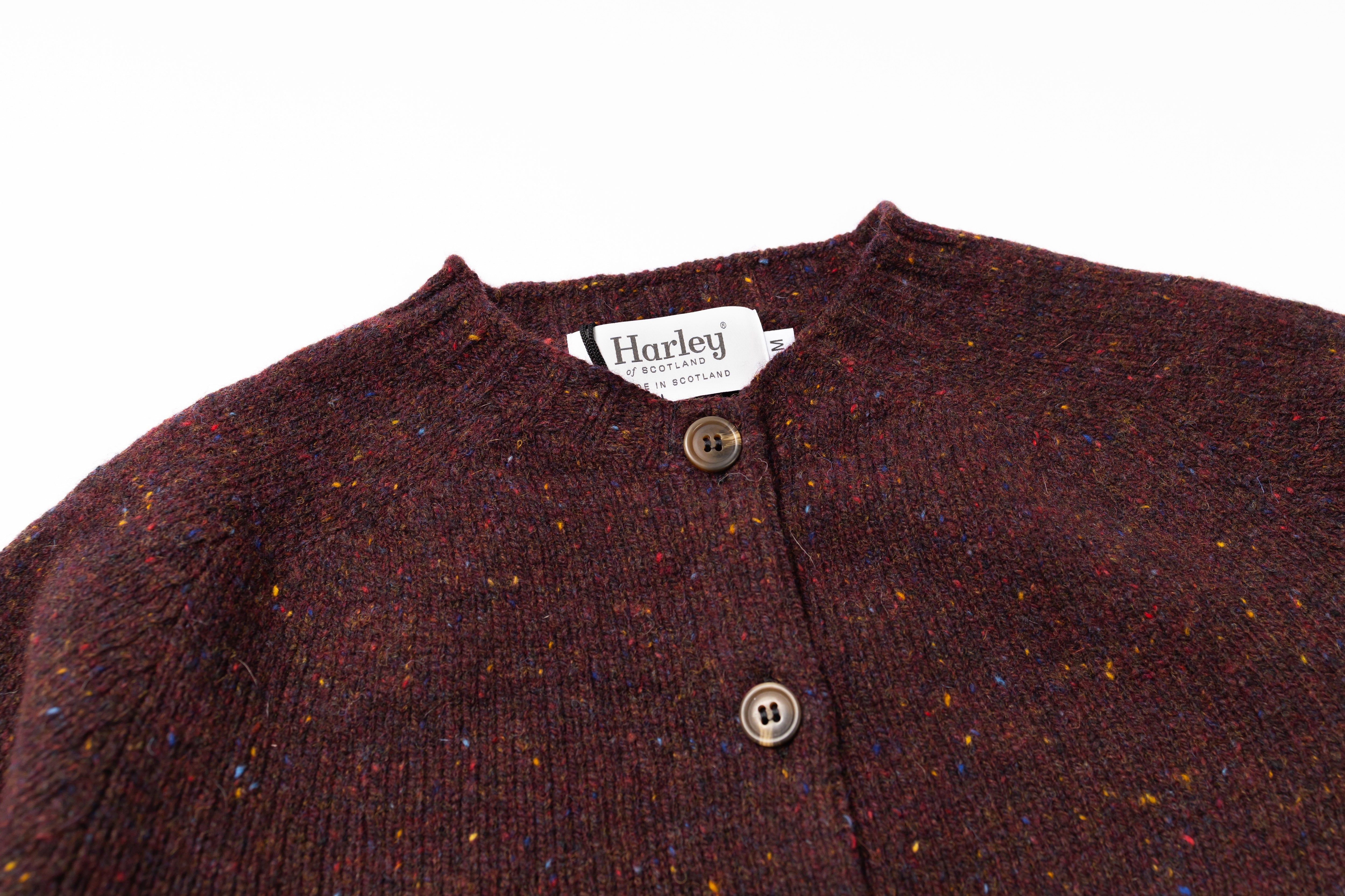 Close-up of a brown textured garment with buttons and a Harley brand tag on a white background