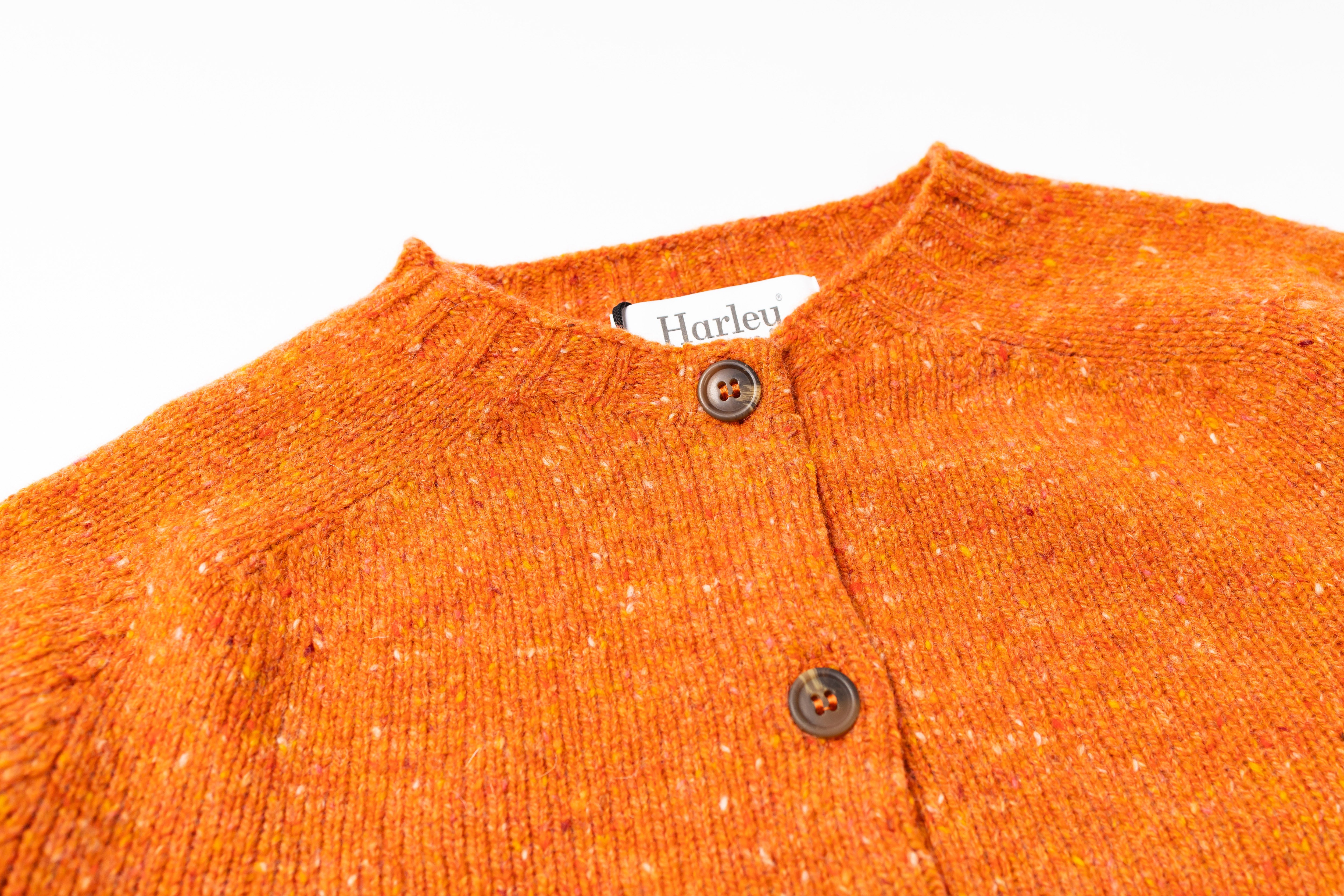 Close-up of an orange textured sweater with buttons on a white background