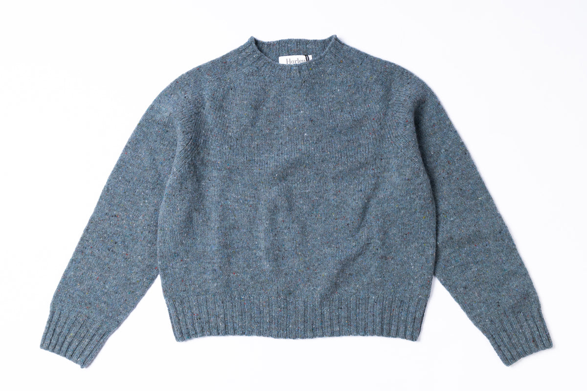 A heathered slate blue knit sweater with a crew neck, laid flat on a white background.