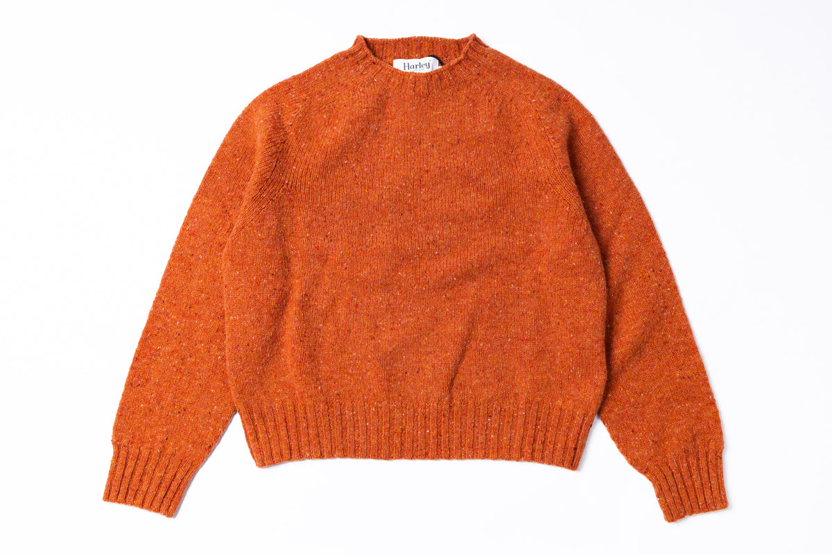 An orange knit sweater with a textured heathered finish, featuring a crew neck, long sleeves, and ribbed cuffs and hem, laid flat against a white background.