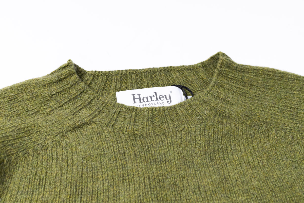 Close-up of a ribbed knit sweater in olive green, showing the inner collar label that reads Harley Scotland.