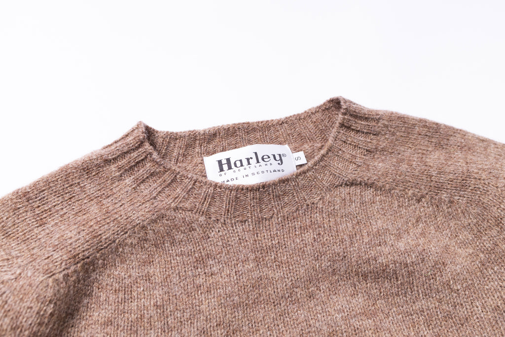 Brown sweater with 'Harley' label on a white background zoomed in