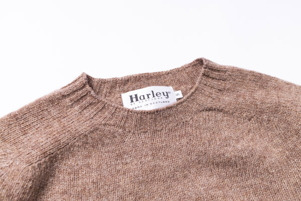 Brown sweater with 'Harley' label on a white background zoomed in