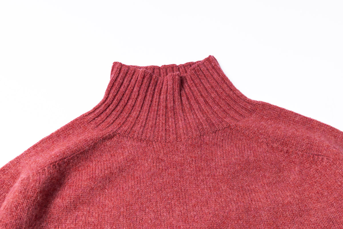 Close-up of a ribbed knit turtleneck sweater in a heathered dusty rose red color, showing the texture and collar detail against a plain white background.